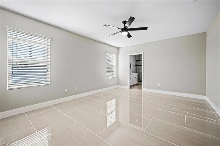 Spare room with light tile patterned floors, baseboards, and ceiling fan