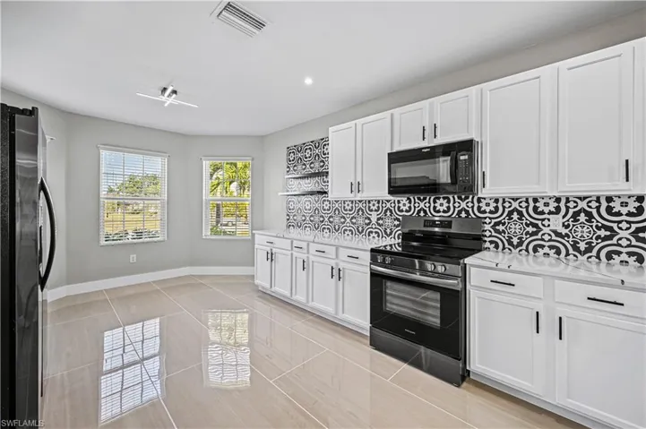 Kitchen with visible vents, stainless steel appliances, light countertops, white cabinets, and backsplash