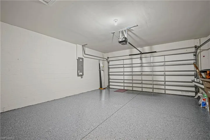Garage with electric panel, a garage door opener, and concrete block wall