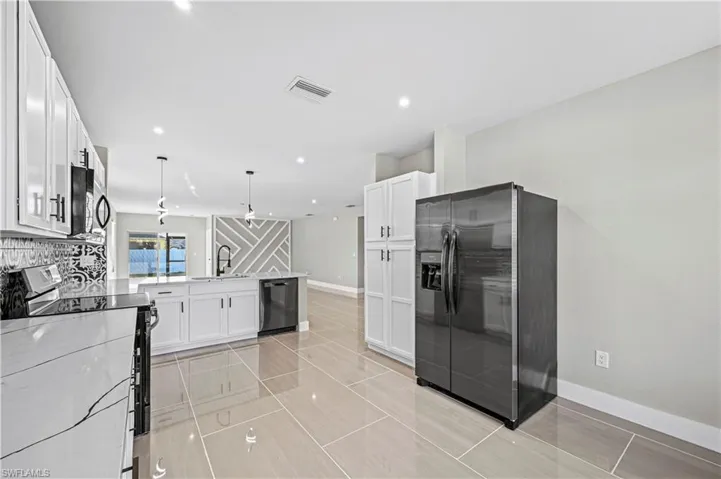 Kitchen with visible vents, dishwasher, fridge with ice dispenser, electric range, and a sink
