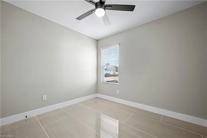 Unfurnished room featuring light tile patterned floors, baseboards, and ceiling fan