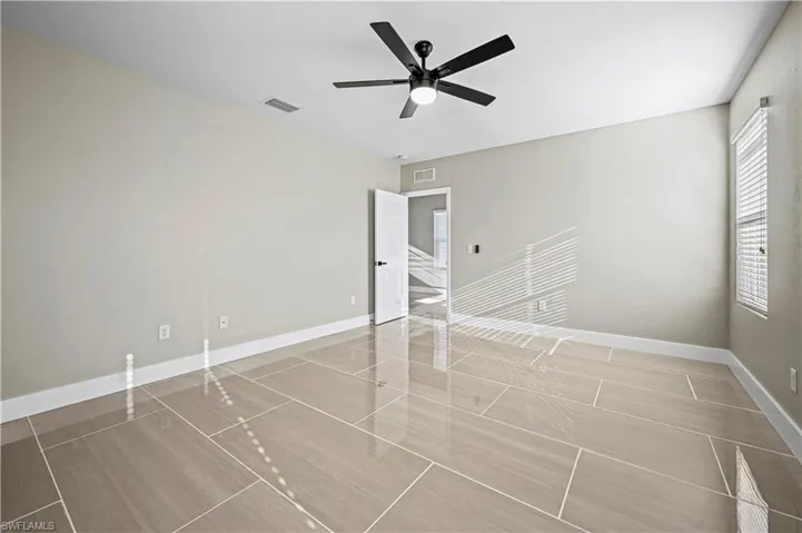 Empty room featuring visible vents, baseboards, and a ceiling fan