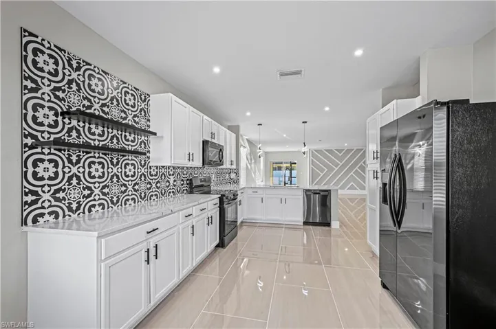 Kitchen with visible vents, black appliances, a peninsula, and white cabinets