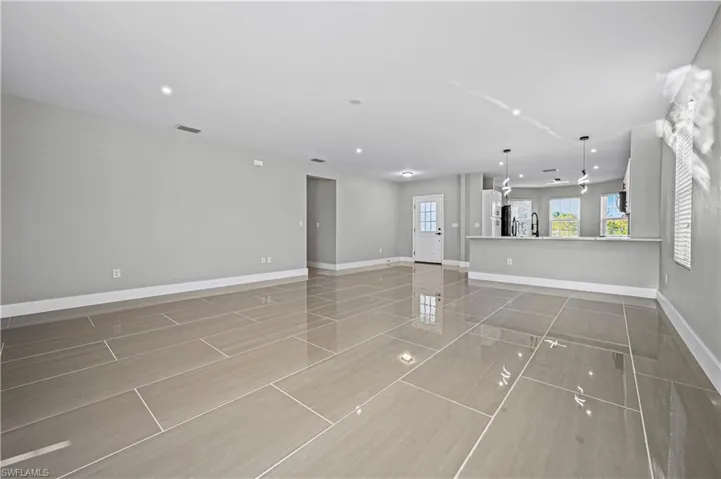 Unfurnished living room featuring a sink, visible vents, baseboards, and recessed lighting