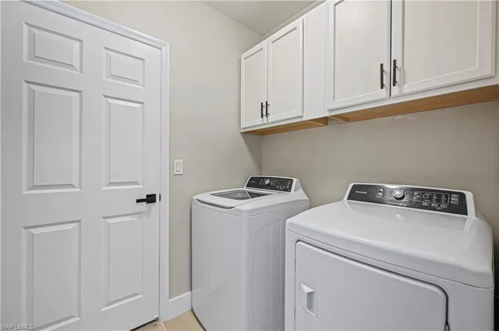 Laundry area featuring washing machine and dryer, cabinet space, and baseboards