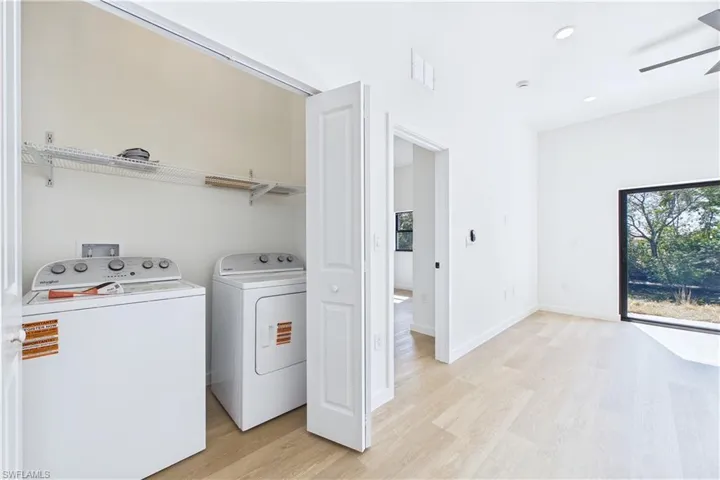 Laundry area with light wood-type flooring, ceiling fan, washer and clothes dryer, and recessed lighting
