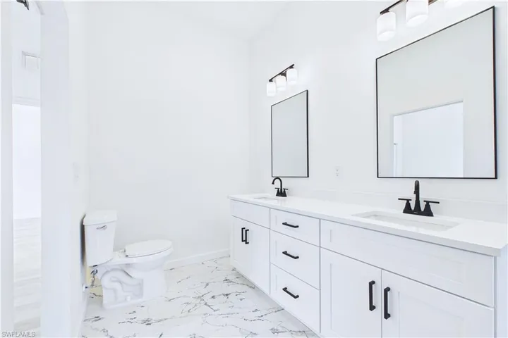 Bathroom featuring double vanity and light marble finish flooring