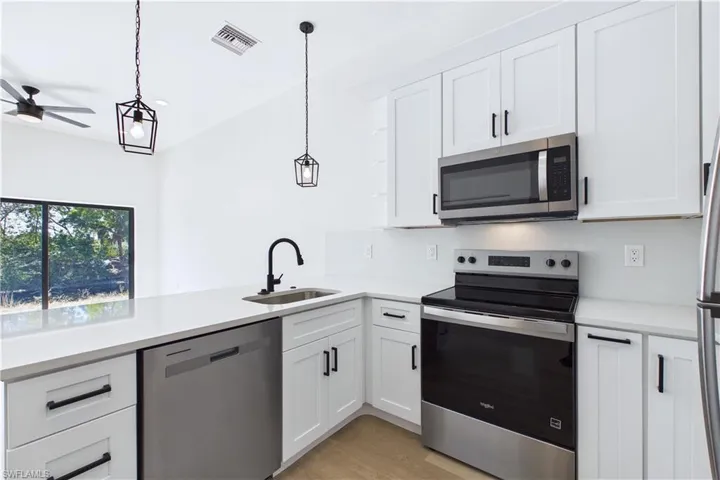 Kitchen featuring stainless steel appliances, white cabinetry, and a ceiling fan