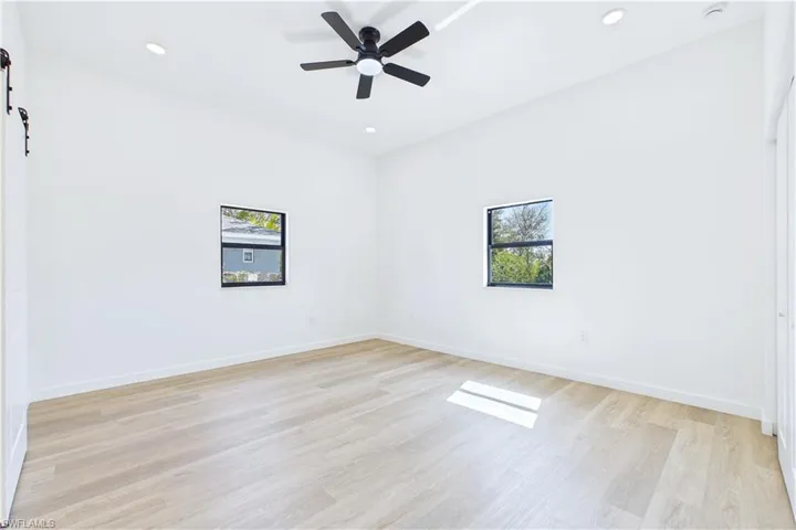 Spare room featuring plenty of natural light, a barn door, light wood-type flooring, ceiling fan, and recessed lighting