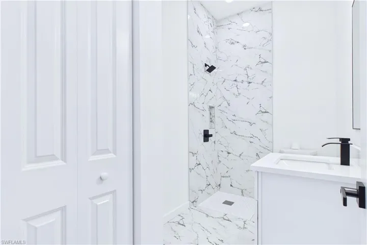 Full bath with a marble finish shower, vanity, and light marble finish flooring