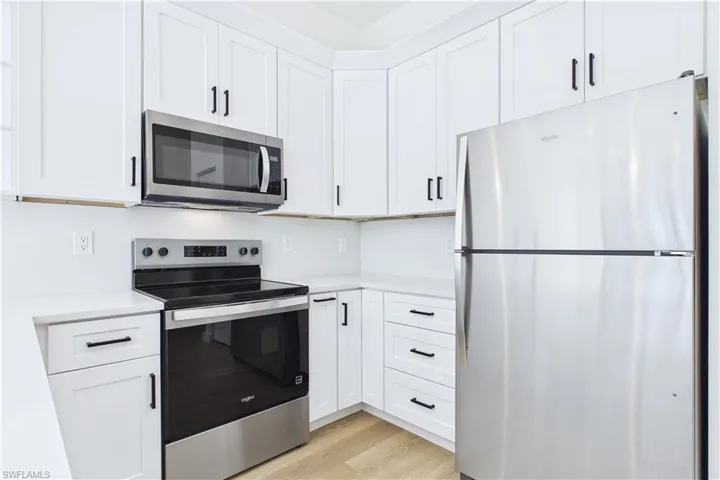 Kitchen featuring stainless steel appliances, white cabinets, and light wood-style flooring