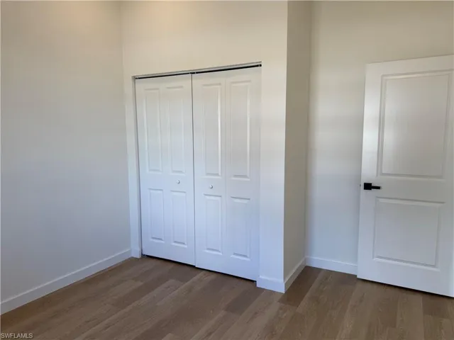 Unfurnished bedroom with dark wood finished floors and a closet
