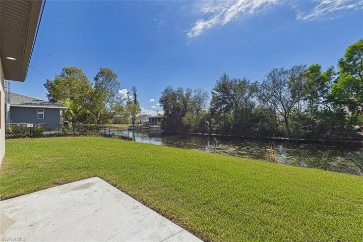 View of green lawn featuring a water view and a patio area