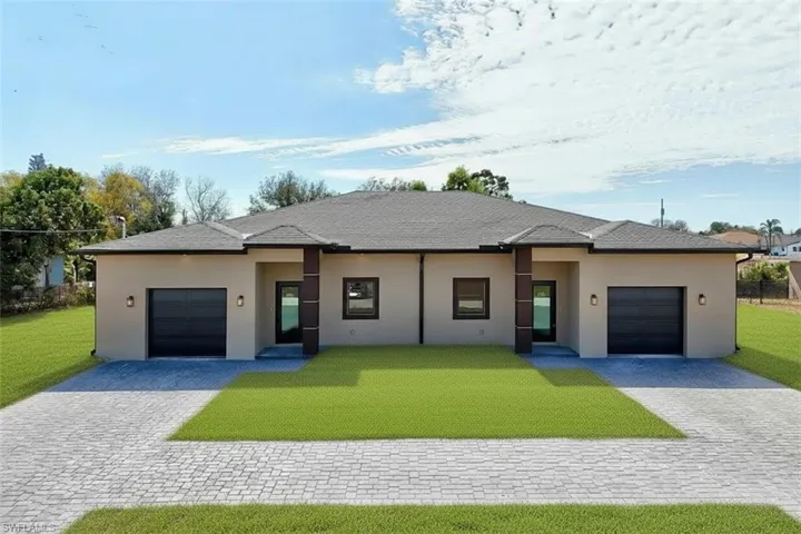 View of front of property featuring a garage, a front yard, decorative driveway, and stucco siding