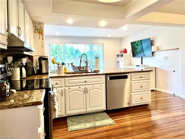 Kitchen featuring light hardwood / wood-style flooring, white cabinetry, stainless steel dishwasher, and sink