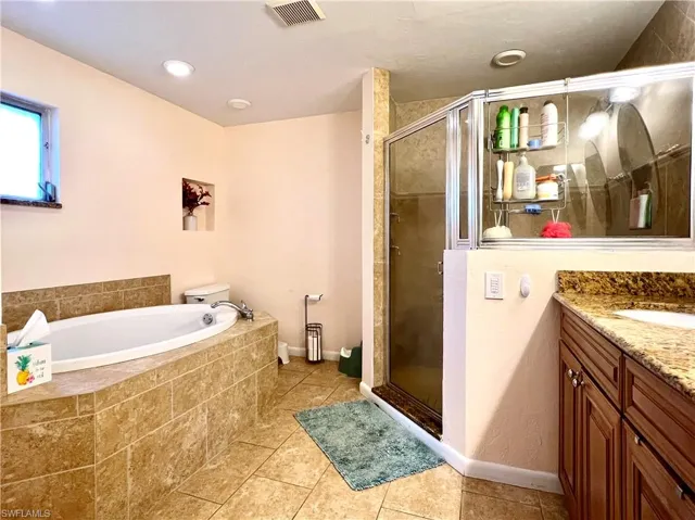 Bathroom with tile patterned flooring, vanity, and independent shower and bath