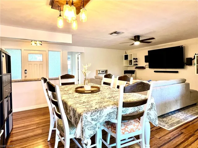 Dining area with ceiling fan with notable chandelier and hardwood / wood-style flooring