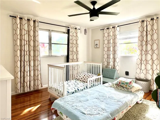Bedroom with multiple windows, ceiling fan, and hardwood / wood-style floors
