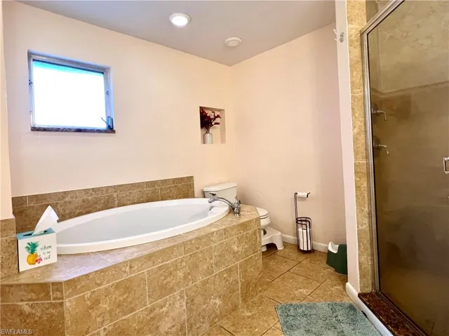 Bathroom featuring tile patterned flooring, independent shower and bath, and toilet