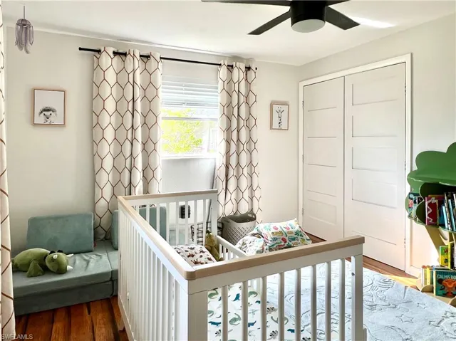 Bedroom featuring a crib, a closet, ceiling fan, and dark hardwood / wood-style floors
