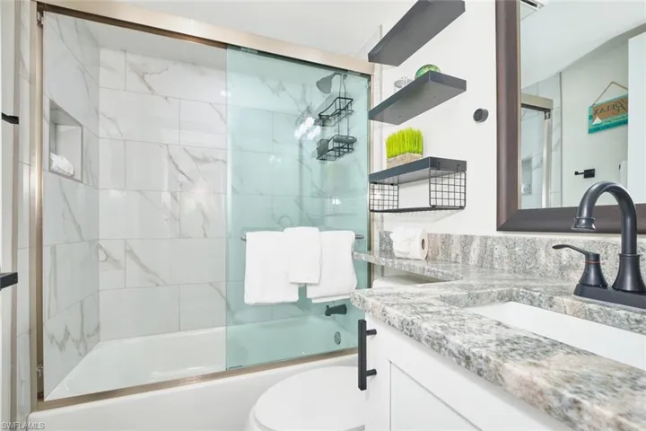 Bathroom with vanity and bath / shower combo with glass door