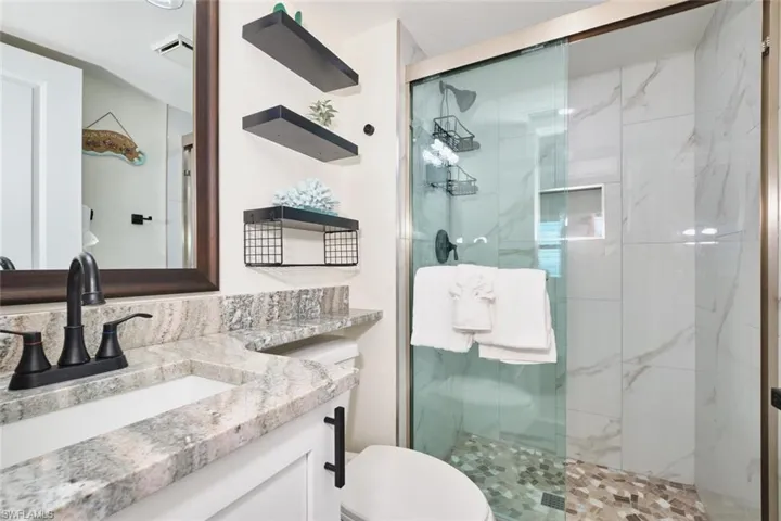Full bath featuring a marble finish shower and vanity