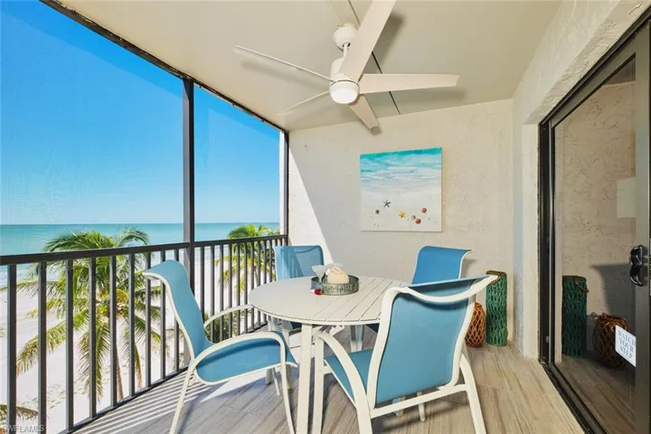 Sunroom / solarium with view of water and beach, wood finished floors, floor to ceiling windows, and a textured wall