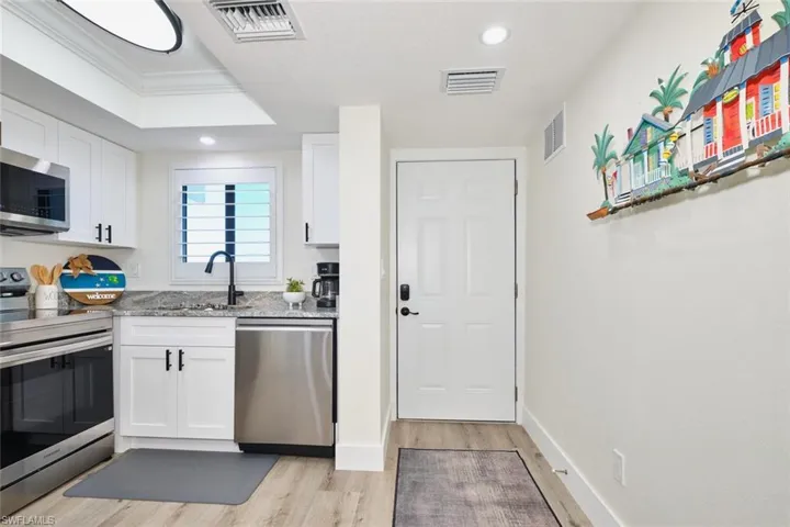 Kitchen featuring stainless steel appliances, light stone countertops, white cabinetry, light wood finished floors, and recessed lighting
