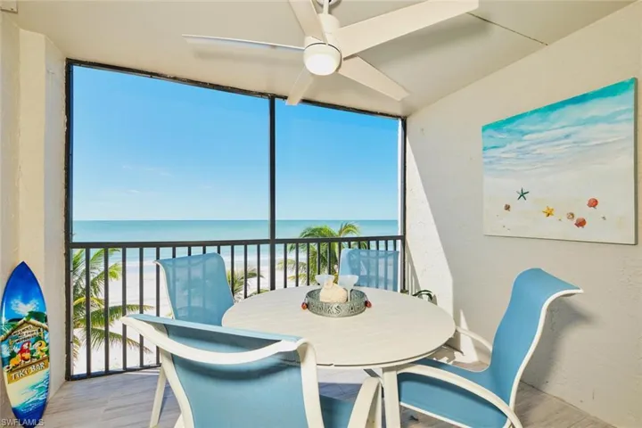 Sunroom / solarium featuring floor to ceiling windows, view of water and beach, a textured wall, and wood finished floors