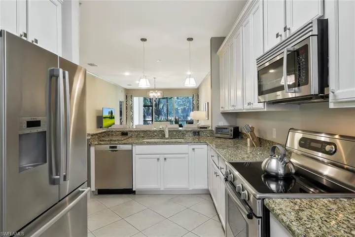 Kitchen with light tile patterned floors, white cabinets, a sink, stainless steel appliances, and pendant lighting