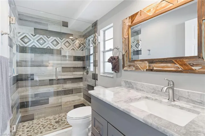 Master Bathroom with tile shower, glass door, vanity, and toilet