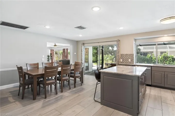 Kitchen featuring ceiling fan, light stone countertops, light tile  flooring, and a center island