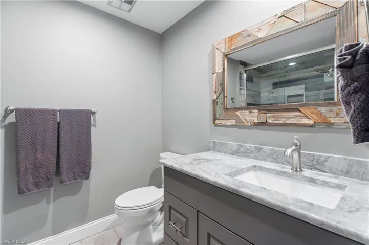 Main Full Bathroom with walk in shower, tile patterned flooring, vanity, and toilet
