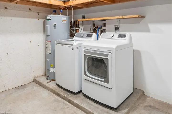 Laundry area in garage with washer and dryer and electric water heater