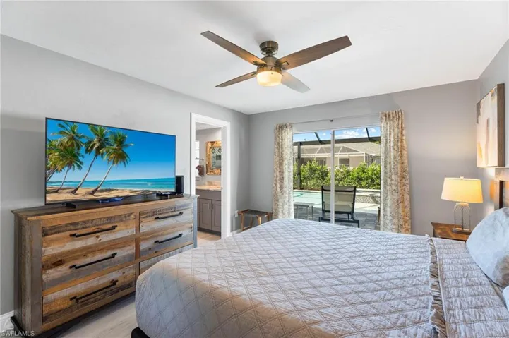 Master Bedroom with light tile flooring, ceiling fan, ensuite bathroom, and access to outside