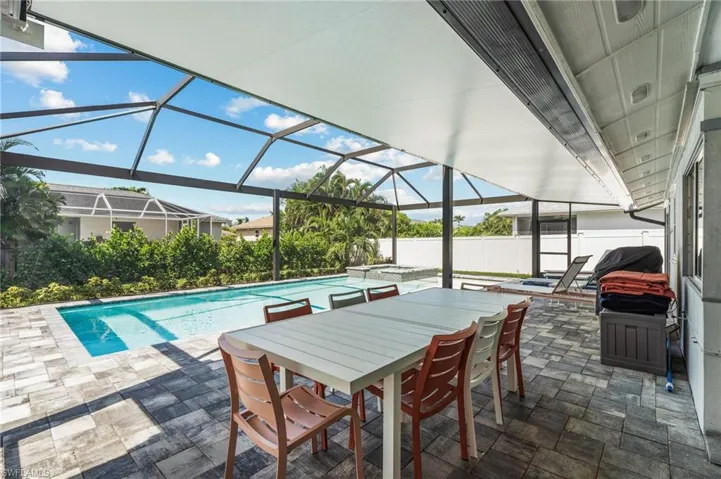 View of pool featuring screened in cage  enclosure, an in ground hot tub, and central AC
