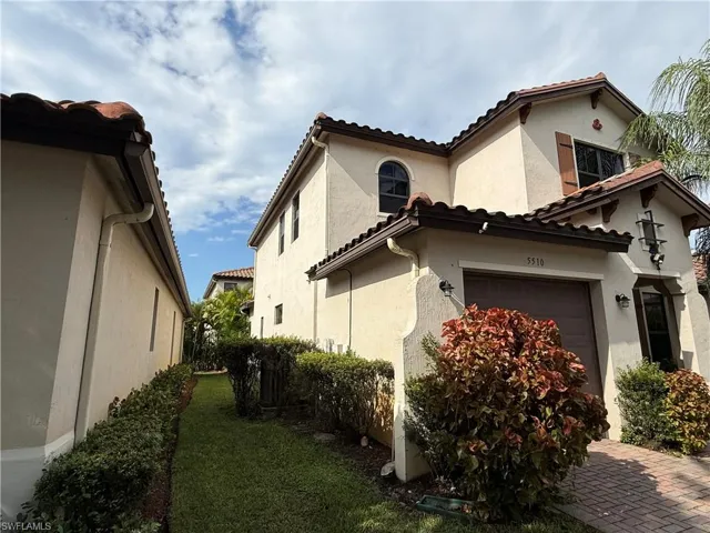 View of property exterior with stucco siding, a garage, a tile roof, and a yard