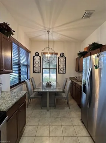 Kitchen featuring stainless steel appliances, dark brown cabinetry, hanging light fixtures, and a chandelier