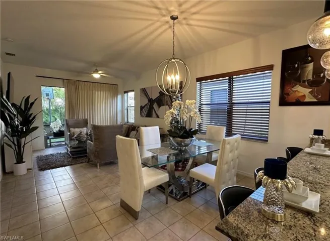 Dining space with light tile patterned floors, ceiling fan, and a chandelier