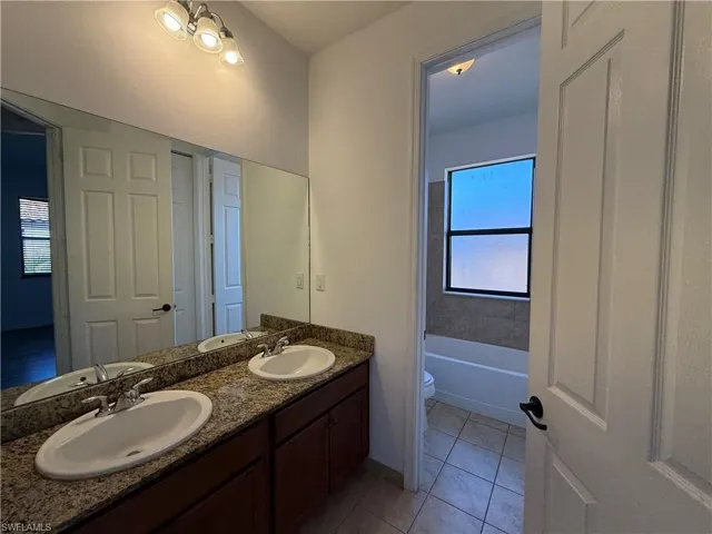 Bathroom with double vanity and light tile patterned floors