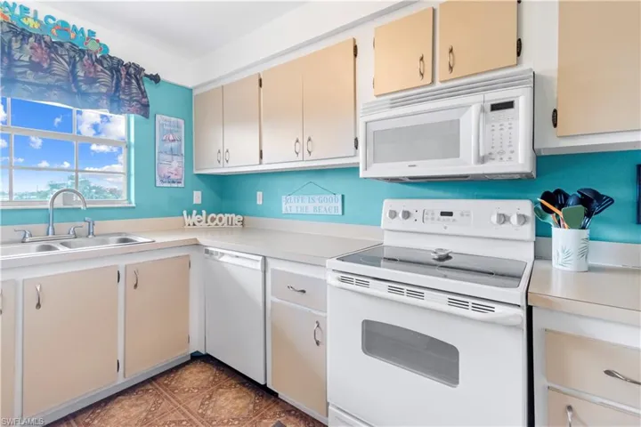 Kitchen featuring white appliances, double sink, and plenty of natural light