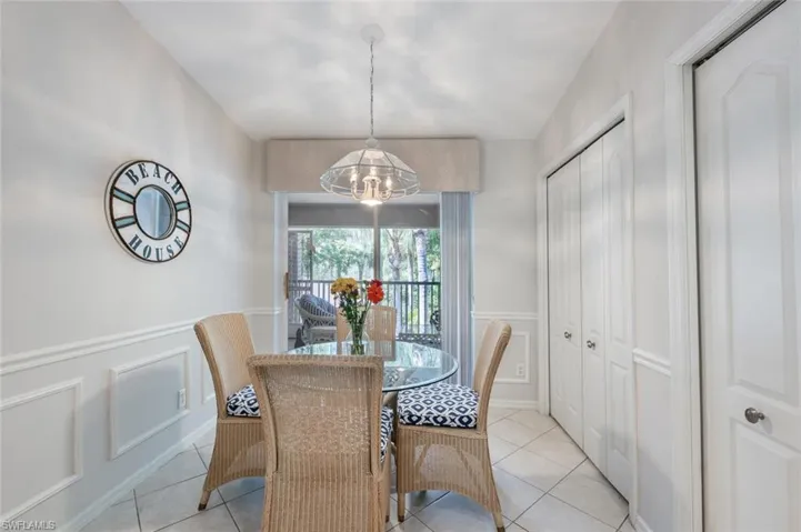 Dining space featuring wainscoting, a decorative wall, light tile patterned floors, and a chandelier