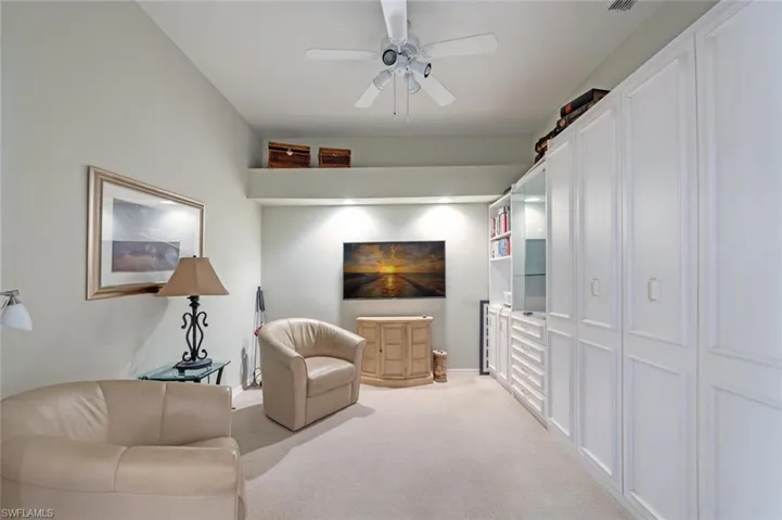 Living room featuring ceiling fan, visible vents, and light colored carpet