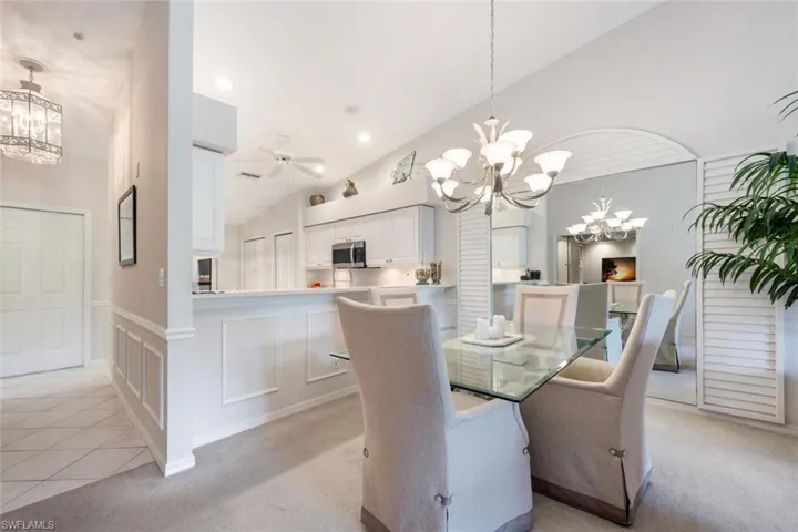 Dining space featuring light carpet, a notable chandelier, and a decorative wall