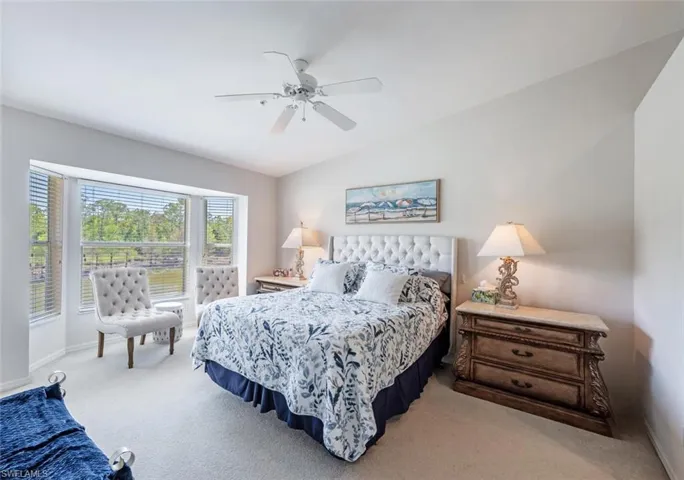 Bedroom featuring baseboards, lofted ceiling, a ceiling fan, and light colored carpet