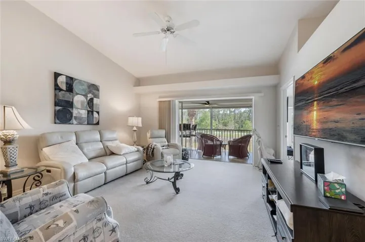Living area with vaulted ceiling, carpet, and a ceiling fan