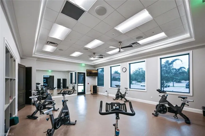 Exercise room with baseboards, visible vents, a paneled ceiling, and a raised ceiling
