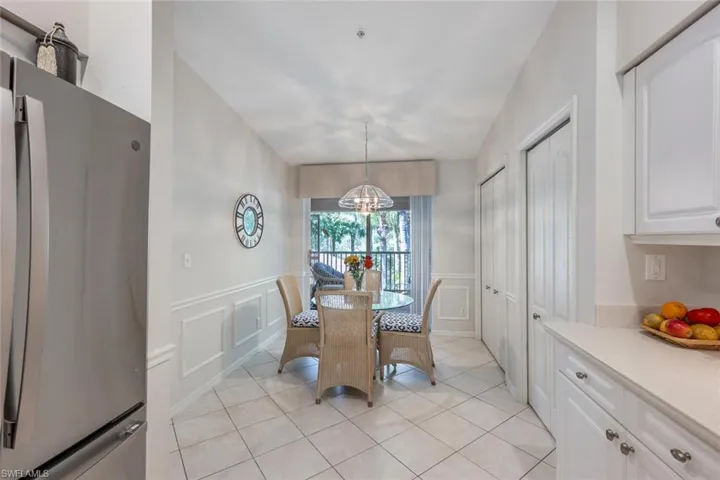 Dining room with a wainscoted wall, light tile patterned floors, a decorative wall, and an inviting chandelier