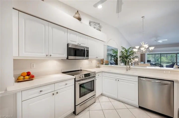 Kitchen featuring lofted ceiling, a sink, ceiling fan with notable chandelier, and appliances with stainless steel finishes