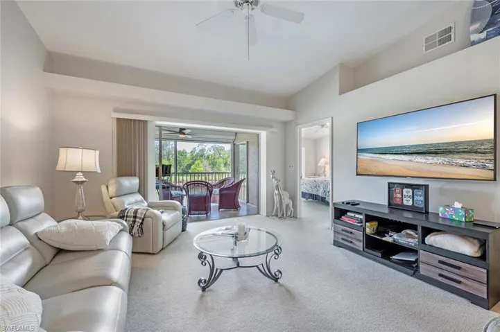 Living room featuring ceiling fan, visible vents, and vaulted ceiling